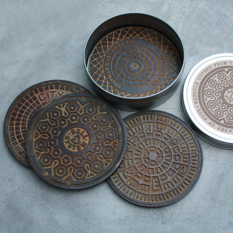 Cast bronze coasters, 3 7/8", set of 4. Each piece is uniquely hand patinated to resemble authentic manholes found on the street of Los Angeles. Signed on the reverse.